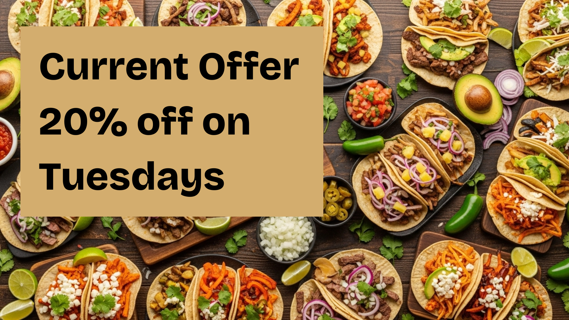 Top shot of a table filled to the brim with different kinds of tacos, garnished with fresh ingredients and different sauces.